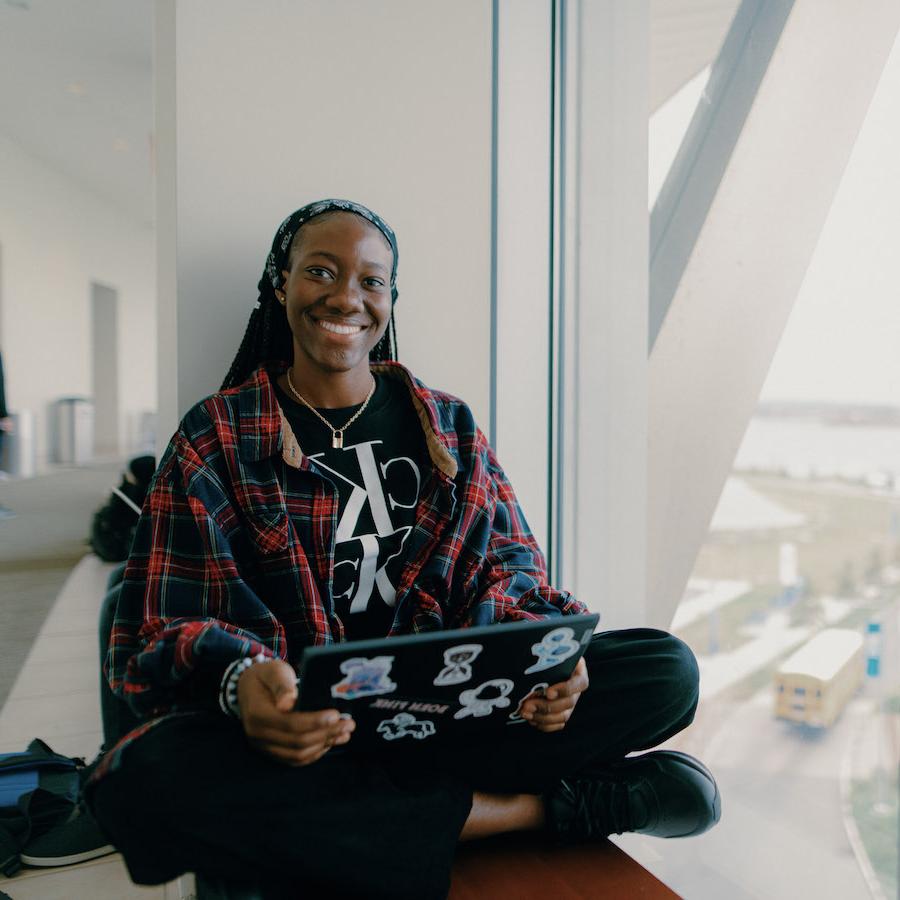 Student smiling and working on a laptop